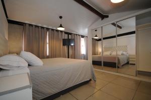 a bedroom with a large bed and a mirror at Apartamento Portal da Ferradura in Búzios