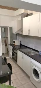 a kitchen with white cabinets and a sink and a dishwasher at Tiny House Funchal in Funchal