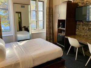 Habitación de hotel con cama, escritorio y TV. en Hôtel Sainte-Anne en Quebec