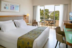 um quarto de hotel com uma cama e uma varanda em Atlantica Miramare Beach em Limassol