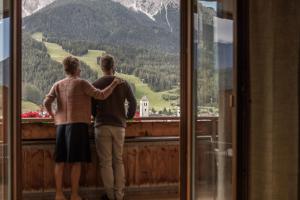 a couple looking out of a window at a mountain at Naturhotel Leitlhof in San Candido