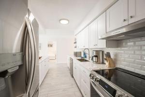 a kitchen with white cabinets and a stainless steel refrigerator at 4BR Sombrero Beach House on Canal w Dock & Pool in Marathon +18 photos