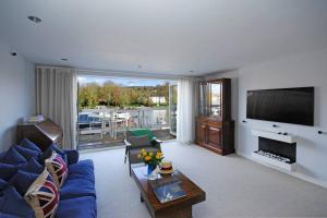 een woonkamer met een blauwe bank en een tv bij The Oars - Riverfront Property in Henley on Thames