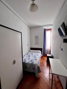 a small bedroom with a bed and a table at Hostal Conde De Alba in Madrid