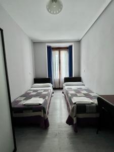 a room with two beds and a window at Hostal Conde De Alba in Madrid