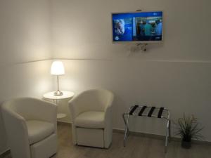 拉古薩的住宿－La Voce del Violino，客厅配有两把椅子和墙上的电视