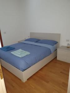 1 dormitorio con 1 cama con sábanas azules y almohadas azules en Bilocale luminoso, ottima posizione, wi-fi e sky en Sondrio