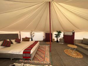a bedroom with a tent with a bed and a couch at Al Salam Desert Camp Bidiya in Badīyah
