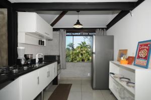 a kitchen with white cabinets and a large window at Apartamento Portal da Ferradura in Búzios