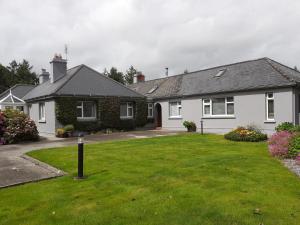 una casa blanca con un patio verde en Conways B&B en Claremorris