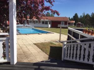 a porch with a white fence and a swimming pool at Norrfällsviken Rum & Kök in Mjällom