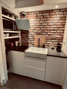 uma cozinha com um lavatório e uma parede de tijolos em This Must Be The Place em Utrecht