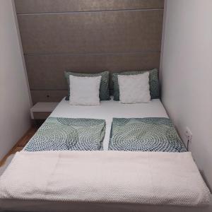Bett in einem kleinen Zimmer mit zwei Kissen in der Unterkunft Carmen deluxe in Novi Sad