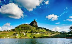 a mountain with a church on top of it next to a lake at Hotel Guatatur in Guatapé