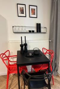 a table with two red chairs and a black table with two vases at Apartamenty Leszka 2, self check in 24h in Poznań