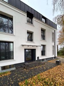 un edificio blanco con ventanas negras y hojas en el suelo en Apartamenty Leszka 2, self check in 24h, en Poznan