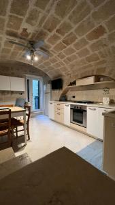 une cuisine avec des placards blancs, une table et un plafond dans l'établissement Il Nido al Castello, à Monopoli