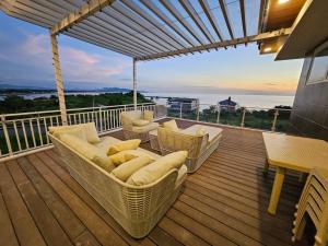 a deck with wicker chairs and a table and the ocean at Villa Pacifica in Nasugbu