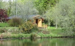 uma cabana de madeira ao lado de uma massa de água em Polgwedhen Lodge em Truro