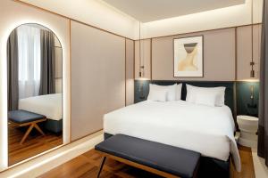 una camera da letto con un grande letto bianco e uno specchio di Hotel Brun a Bologna