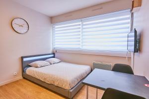 a bedroom with a bed and a table and a clock at Studio Cosy in Pontarlier