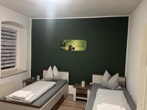 two beds in a room with a green wall at Gästehaus Graupner-Hainichen in Hainichen