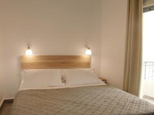 a bedroom with a bed with two lights above it at Thèros in Ermoupoli