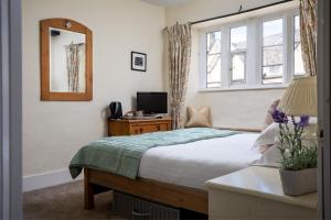 um quarto com uma cama, uma televisão e uma janela em Bantam Tea Rooms em Chipping Campden