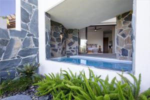 a swimming pool in a house with a stone wall at Adults Only! Ocaso Luxury Villas Entire Property in Rincon