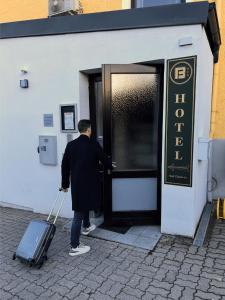 ホルンにあるHotel Blie, Bed & Breakfast, Self Check-inのドアからスーツケースを引き出す男