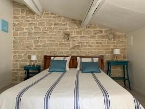 ein Schlafzimmer mit einem großen Bett mit zwei blauen Kissen in der Unterkunft Maison d'hôtes La Chabanaise - Marais Poitevin in Cramchaban