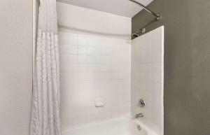 Extended Stay America Select Suites - Denver - Cherry Creek في دنفر: حمام مع دش مع ستارة دش بيضاء