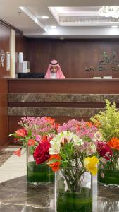 une femme assise dans une salle d'audience avec des fleurs dans des vases dans l'établissement Laten Suites Prince Sultan, à Djeddah