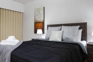 a bedroom with a bed with a black blanket and pillows at 1BR with Balcony Newly Renovated Downtown in Fort McMurray