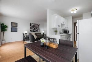 eine Küche und ein Wohnzimmer mit einem Tisch und einem Kühlschrank in der Unterkunft 1BR with Balcony Newly Renovated Downtown in Fort McMurray