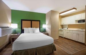 - une chambre avec un grand lit et un mur vert dans l'établissement Extended Stay America Select Suites - Denver - Tech Center South, à Centennial