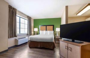 センテニアルにあるExtended Stay America Select Suites - Denver - Tech Center Southのベッド1台、薄型テレビが備わるホテルルームです。
