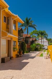 un edificio amarillo con mesas y sillas en una acera en Cabanas da Lua, en Florianópolis