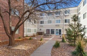 an apartment building with a tree and a sidewalk at Extended Stay America Suites - Denver - Tech Center South - Greenwood Village in Centennial