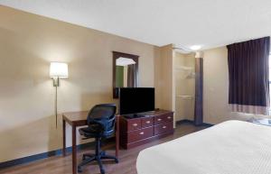 a hotel room with a bed and a desk with a television at Extended Stay America Suites - Denver - Westminster in Westminster