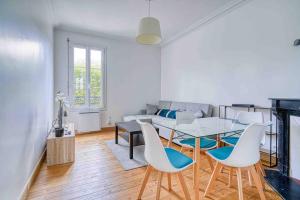 een woonkamer met een tafel en stoelen en een bank bij Appartement dans résidence calme, proche de Paris in La Garenne-Colombes