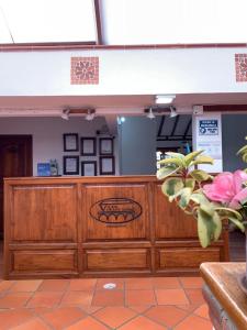 un restaurant avec un comptoir en bois et une fleur rose dans l'établissement Hospederia Villa de los Sáenz, à Villa de Leyva