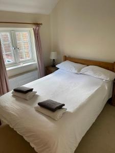 een slaapkamer met een wit bed en 2 handdoeken bij Private Bedrooms in Quaint Oxfordshire Village Cottage in Wantage