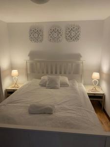 a white bed with two lamps and two pictures on the wall at Apartament Skandynawski in Nowe Worowo