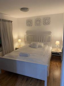 a white bed in a bedroom with two lamps at Apartament Skandynawski in Nowe Worowo