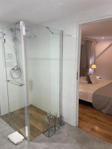 uma casa de banho com uma cabina de duche em vidro e uma cama em Apartament Skandynawski em Nowe Worowo