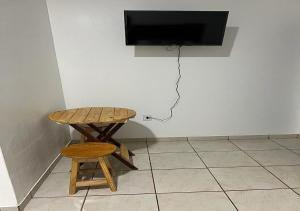 una mesa y un taburete y una TV en la pared en Residencial Margarida APART 1 en Presidente Figueiredo