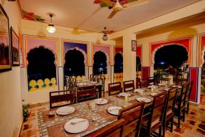 uma sala de jantar com uma mesa longa e cadeiras em Rajputana Heritage em Sawai Madhopur