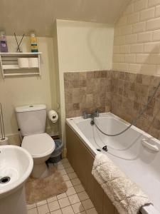 a bathroom with a toilet and a tub and a sink at Private Bedrooms in Quaint Oxfordshire Village Cottage in Wantage