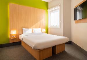 um quarto com uma cama grande e uma parede verde em B&B HOTEL Limoges Centre Gare em Limoges
